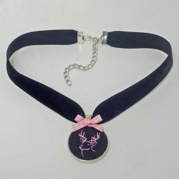 Kette aus schwarzem Samt Medaillon rosa bestickt liegend